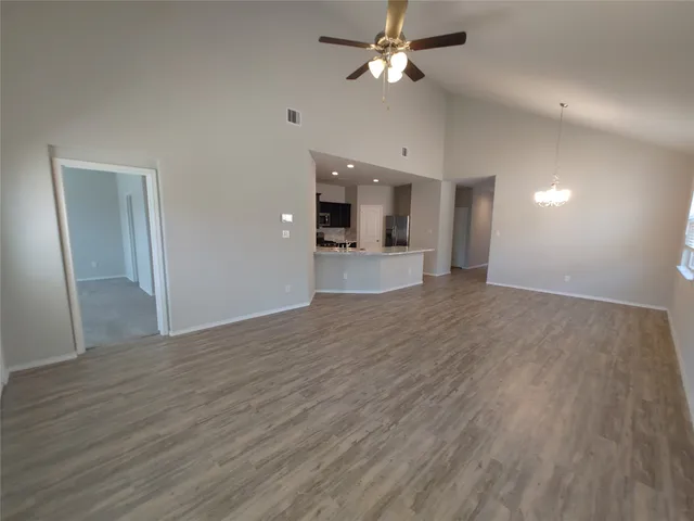 a view of empty room with wooden floor and ceiling fan
