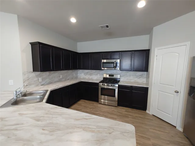 a kitchen with granite countertop a refrigerator and a stove top oven