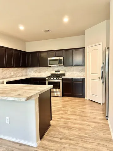 a kitchen with stainless steel appliances granite countertop a stove a sink and a refrigerator