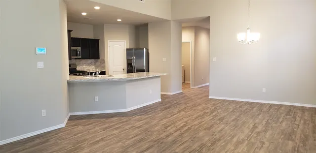a view of a kitchen with kitchen island a sink wooden floor and black appliances
