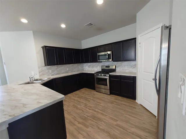 a kitchen with stainless steel appliances kitchen island granite countertop a refrigerator and a sink