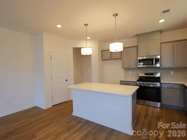 a kitchen with stainless steel appliances granite countertop a sink a stove and a wooden floors