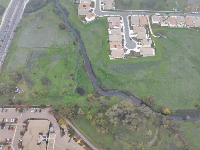 an aerial view of huge green field with lots of green plants and covered by side of the house