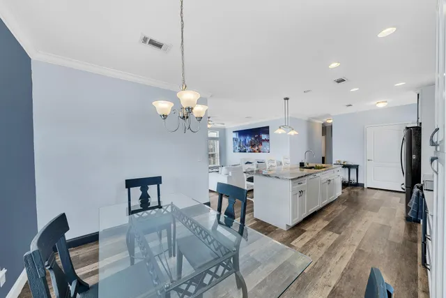 a large white kitchen with lots of counter space dining table and a chandelier