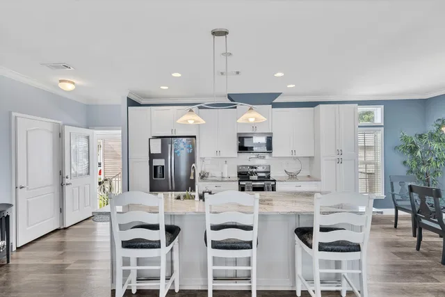 a kitchen with stainless steel appliances kitchen island granite countertop a stove and white cabinets