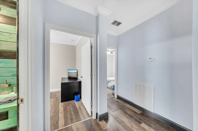 a view of a hallway with wooden floor and a bathroom