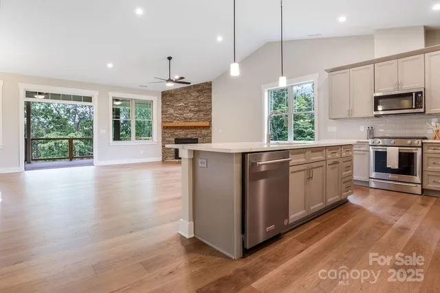 a large kitchen with stainless steel appliances granite countertop a refrigerator a stove a sink dishwasher and a oven with wooden floor