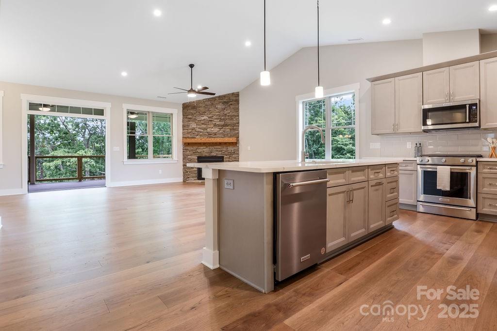 21 Craftsman Overlook Ridge Arden, NC 28704 - Photo 4 of 36 a kitchen with stainless steel appliances granite countertop a stove top oven a sink dishwasher a refrigerator and a dining table with wooden floor