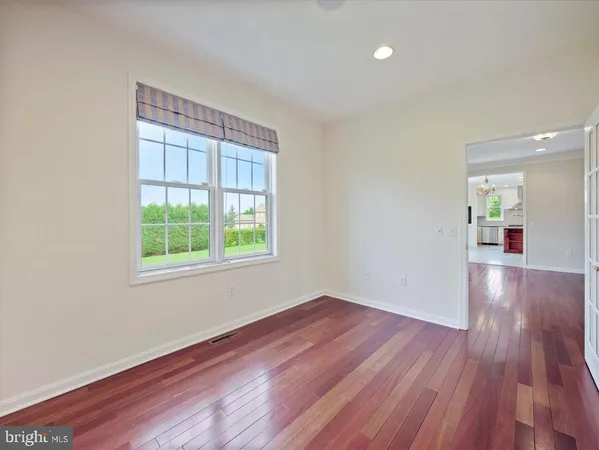 a view of an empty room with wooden floor and windows