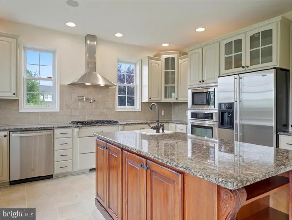 a kitchen with stainless steel appliances granite countertop a sink dishwasher a stove and a refrigerator with wooden floor