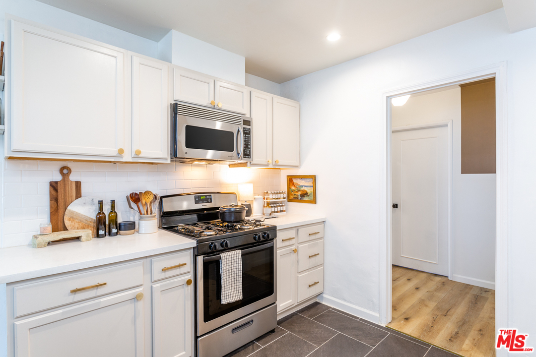1663 South Rimpau Boulevard Los Angeles, CA 90019 - Photo 11 of 21 a kitchen with granite countertop a stove a sink and a microwave