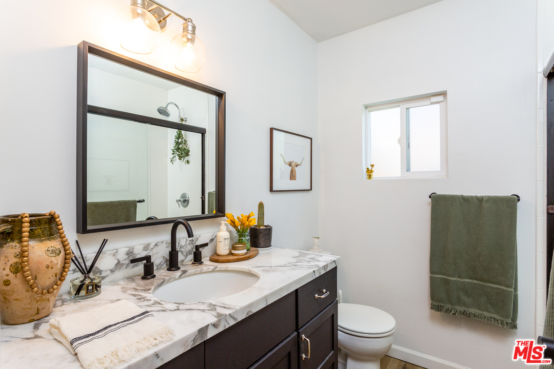 1663 South Rimpau Boulevard Los Angeles, CA 90019 - Photo 15 of 21 a bathroom with a granite countertop sink a toilet and mirror