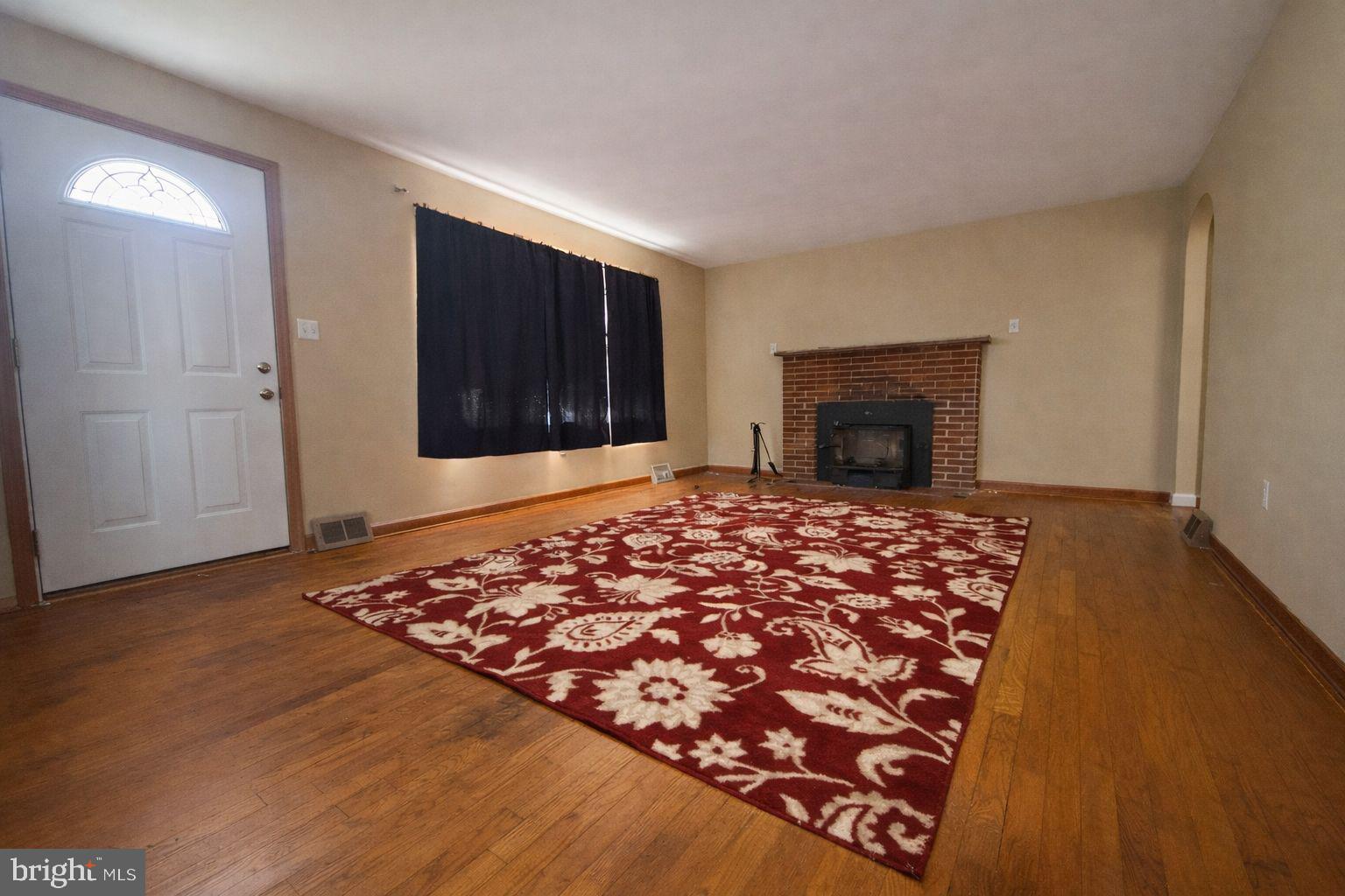 3891 Coseytown Road Greencastle, PA 17225 - Photo 16 of 50 an empty room with wooden floor fireplace and windows