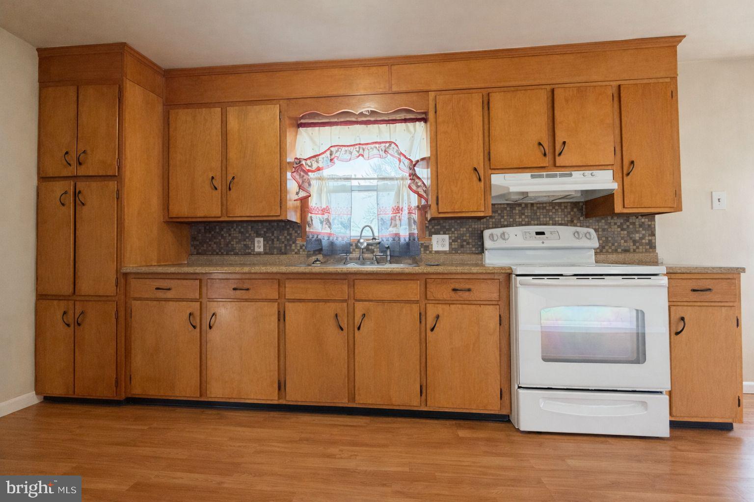 3891 Coseytown Road Greencastle, PA 17225 - Photo 8 of 50 a kitchen with stainless steel appliances granite countertop a stove a sink and white cabinets with wooden floor