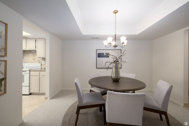 6936 South 775 East, Unit B Midvale, UT 84047 - Photo 8 of 33 Dining room with light carpet, a tray ceiling, a chandelier, crown molding, and light tile patterned floors