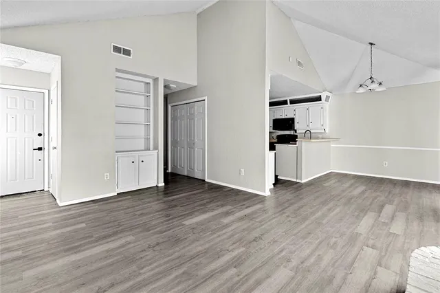 an empty room with wooden floor closet and windows