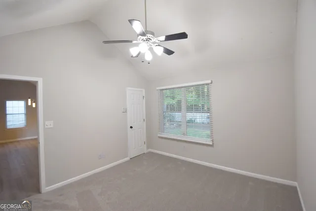 an empty room with windows and fan