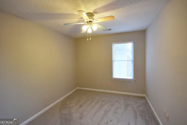 an empty room with windows and fan