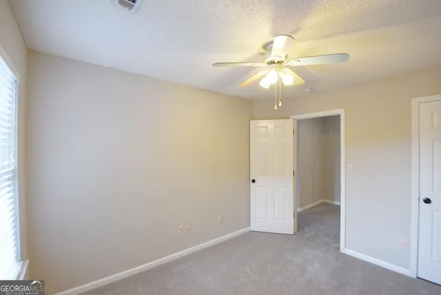 an empty room with a ceiling fan and a window