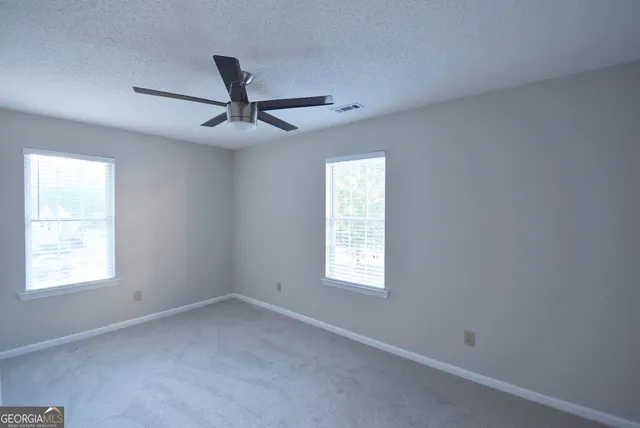 an empty room with a window and a ceiling fan