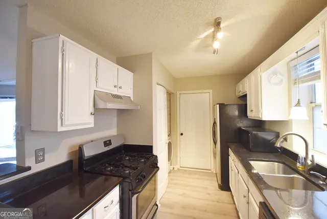a kitchen with granite countertop a sink stainless steel appliances and cabinets
