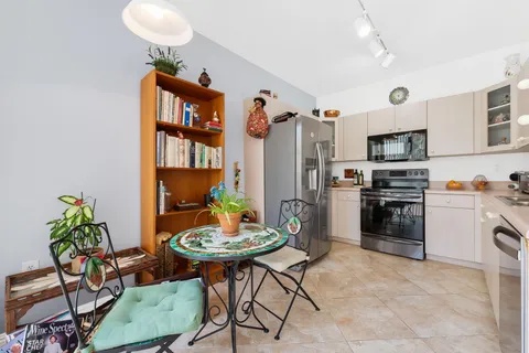 a kitchen with stainless steel appliances a stove a refrigerator cabinets and a dining table