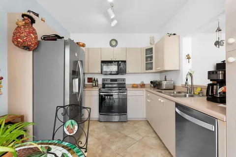 a kitchen with stainless steel appliances granite countertop a sink a stove a refrigerator a chimney a refrigerator and a stove