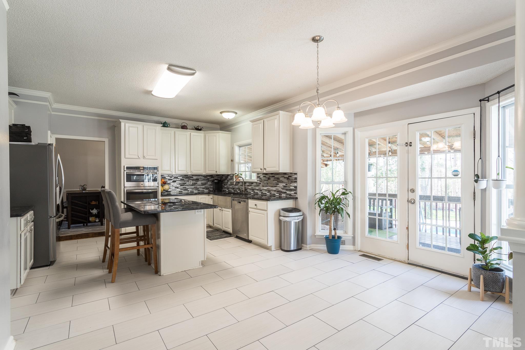 4900 Goosedown Court Raleigh, NC 27604 - Photo 16 of 41 The large kitchen has been beautifully upgraded with granite counters and tile backsplash. A lot of cabinet space for all of your cooking needs, stainless steel appliances and French doors that lead to the back porch and yard.