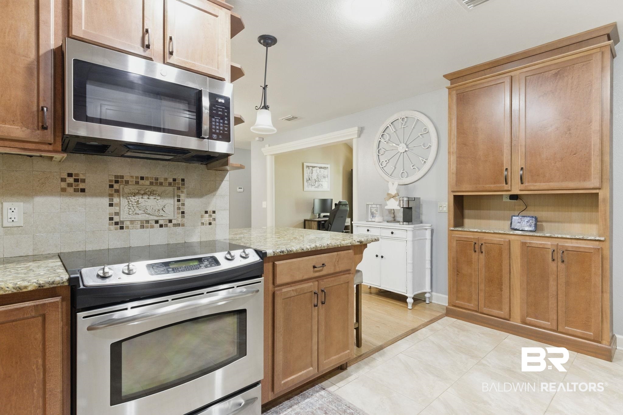 32345 River Lake Road Seminole, AL 36574 - Photo 15 of 56 Kitchen with decorative light fixtures, appliances with stainless steel finishes, brown cabinetry, light stone countertops, and backsplash