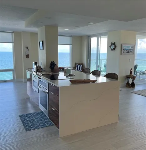 a living room with stainless steel appliances kitchen island granite countertop furniture and a rug