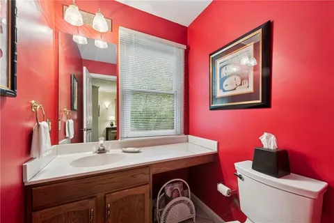 a bathroom with a sink a mirror a toilet and a window