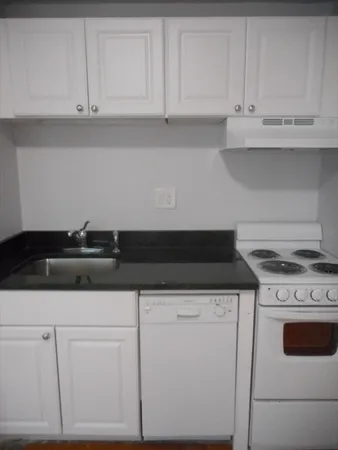 a kitchen with granite countertop white cabinets and white appliances
