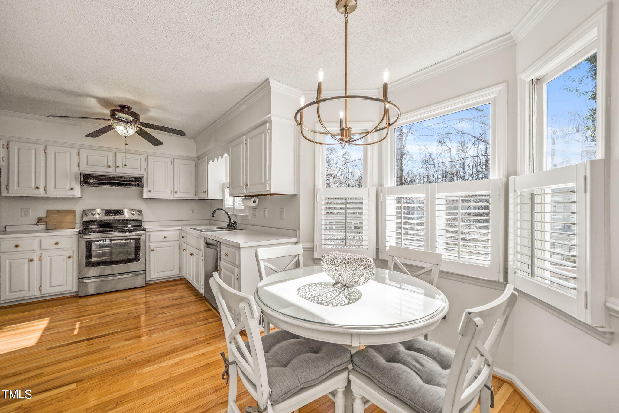 4117 Cary Oaks Drive Apex, NC 27539 - Photo 12 of 38 a kitchen with stainless steel appliances kitchen island granite countertop a stove a sink a dining table and chairs with wooden floor