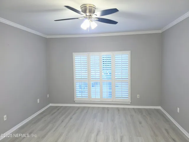 an empty room with wooden floor fan and windows