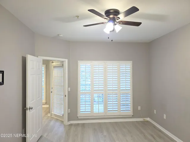 a view of an empty room with a window and a ceiling fan