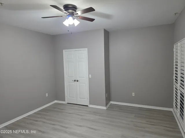 a view of an empty room and chandelier fan