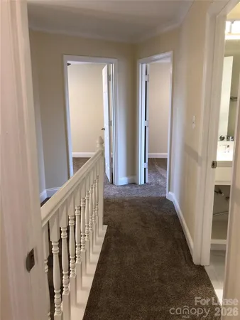 a view of a hallway with wooden floor and stairs