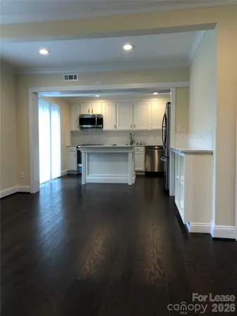 a living room with hard wood floors and a kitchen