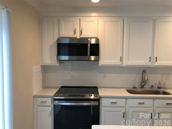 a kitchen with stainless steel appliances granite countertop white cabinets a microwave oven and sink