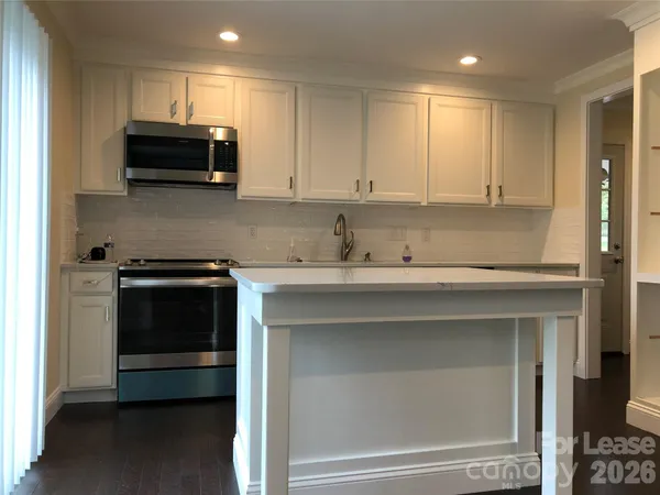 a kitchen with granite countertop white cabinets and stainless steel appliances