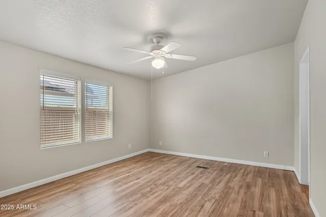 a view of empty room with wooden floor and fan