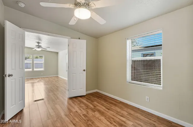 a view of an empty room with wooden floor and a window