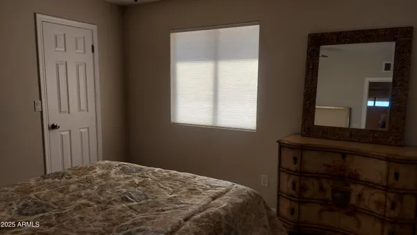 a bedroom with a bed and a lamp on dresser