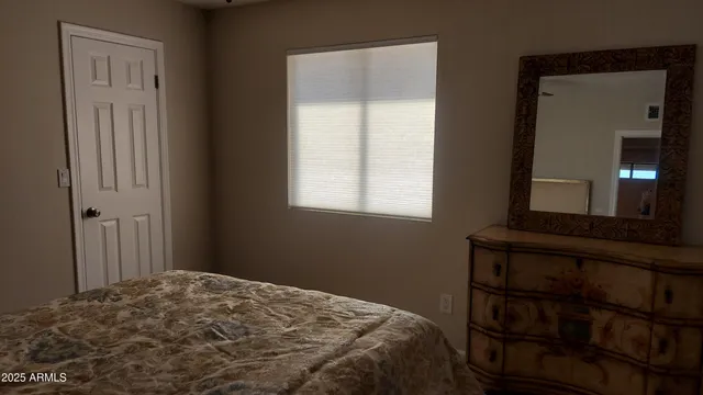 a bedroom with a bed and a lamp on dresser