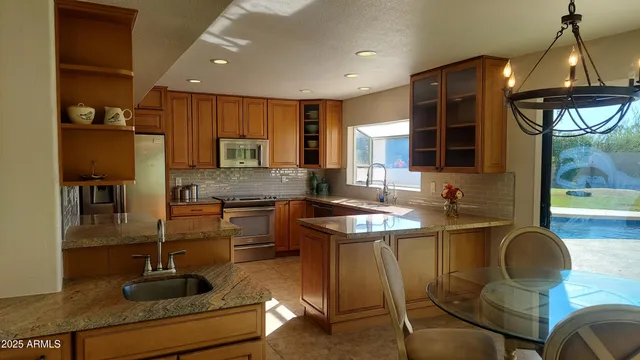 a kitchen with stainless steel appliances granite countertop a sink a stove and a refrigerator