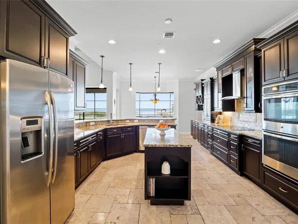 a kitchen with stainless steel appliances granite countertop a stove a sink and a refrigerator