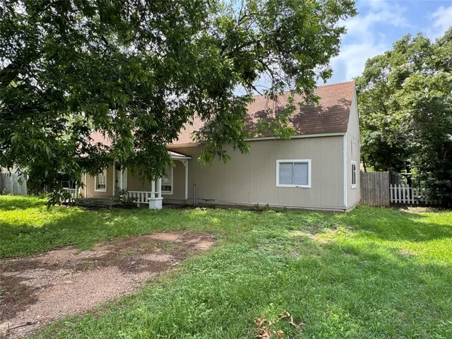a backyard of a house with plants and large tree