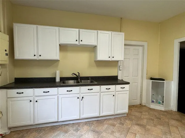 a kitchen with granite countertop white cabinets and sink