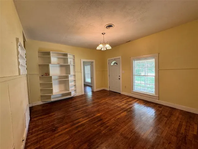 an empty room with wooden floor closet and windows