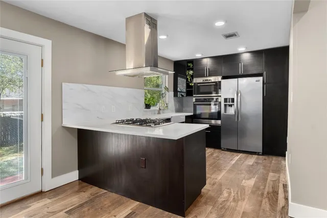 a kitchen with kitchen island a counter top space cabinets and stainless steel appliances